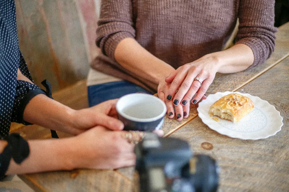 Two people at a café table, coffee and a pastry between them.